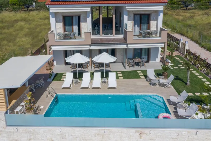 Vue aérienne d'une piscine rectangulaire devant un bâtiment beige à deux étages.