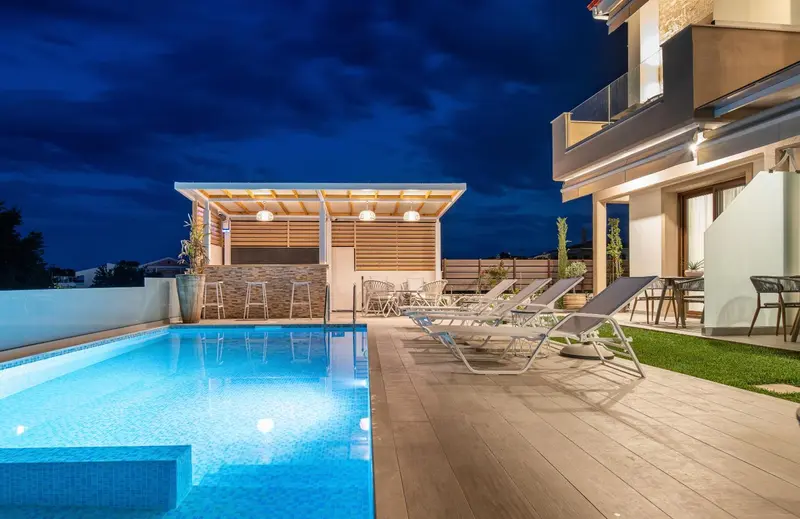 Piscine illuminée avec chaises longues et espace détente extérieur.
