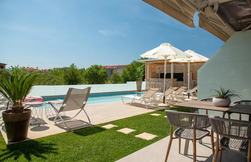 Espace extérieur avec piscine, chaises longues et végétation luxuriante.