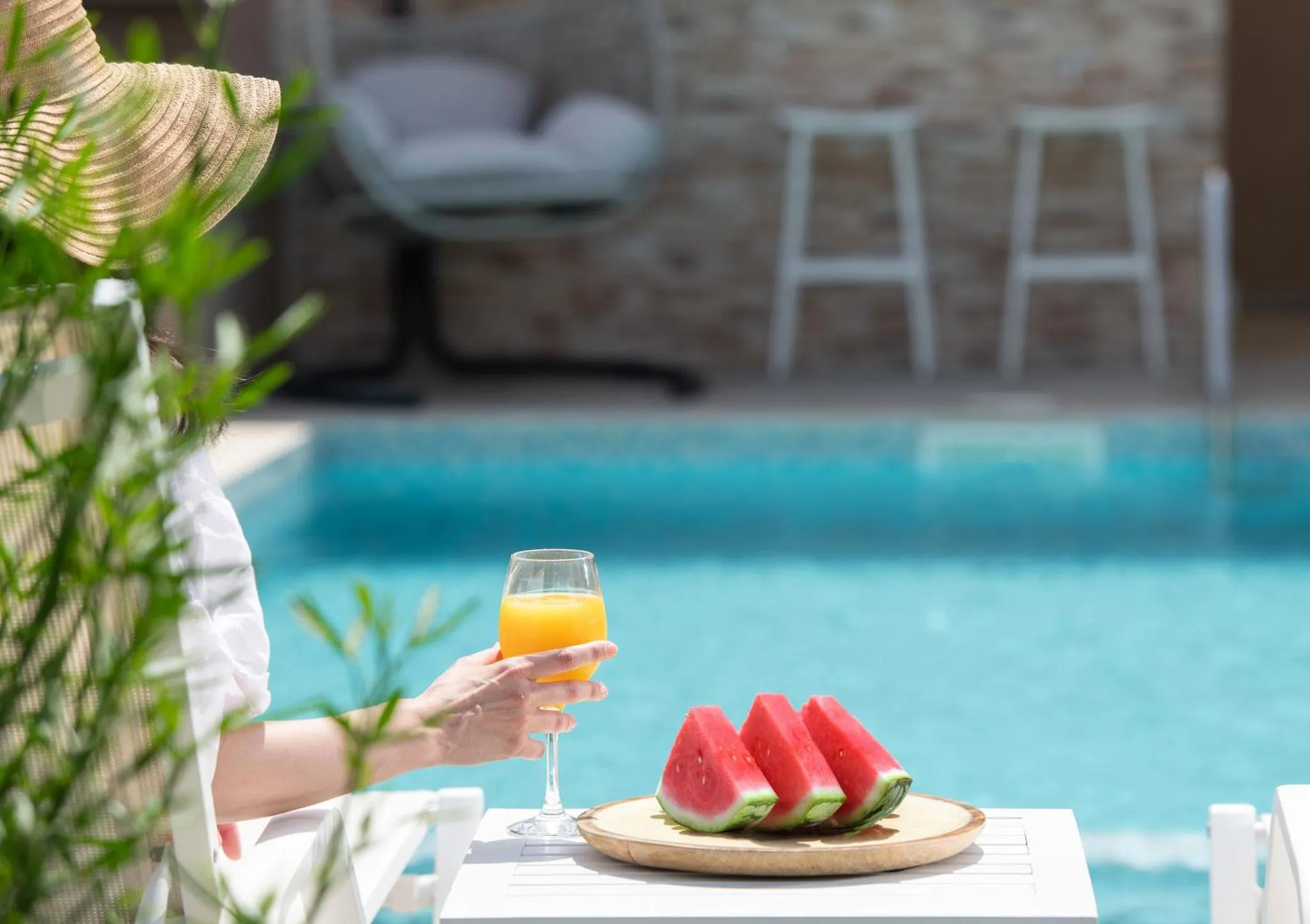 Une personne déguste une boisson et des fruits au bord d'une piscine.