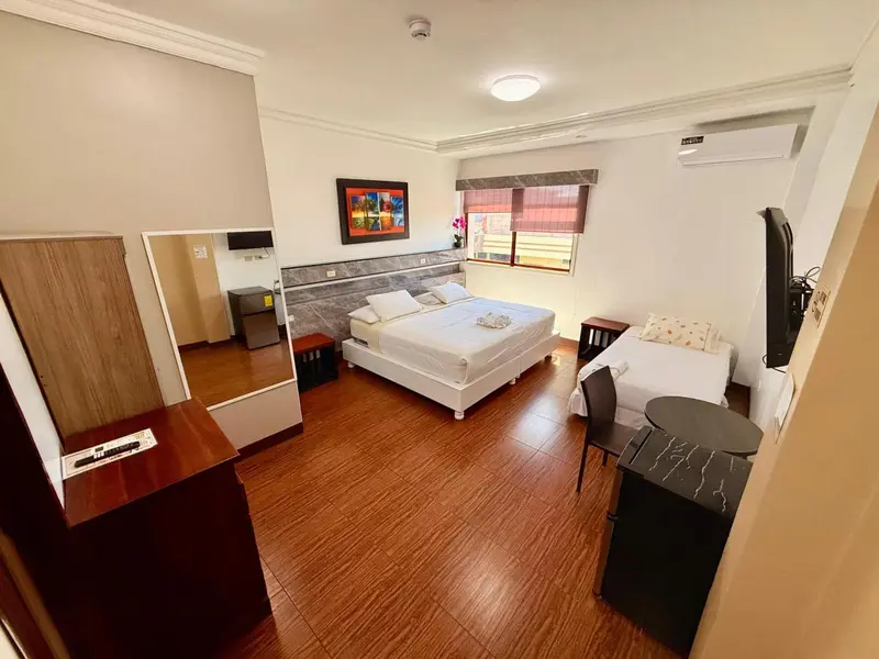 Chambre lumineuse avec un grand lit et un coin repas.