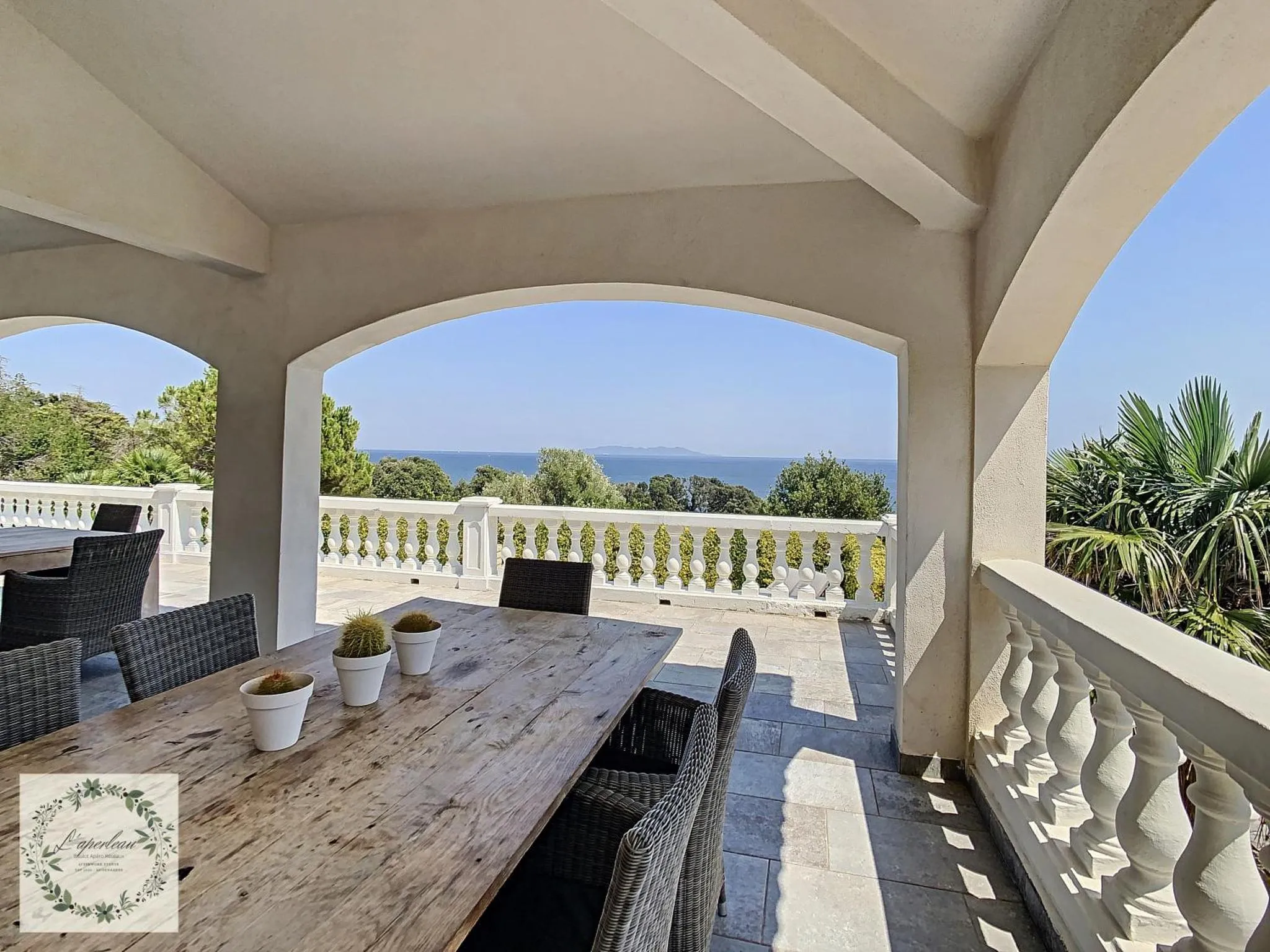Terrasse ombragée avec table à manger et vue sur la mer.