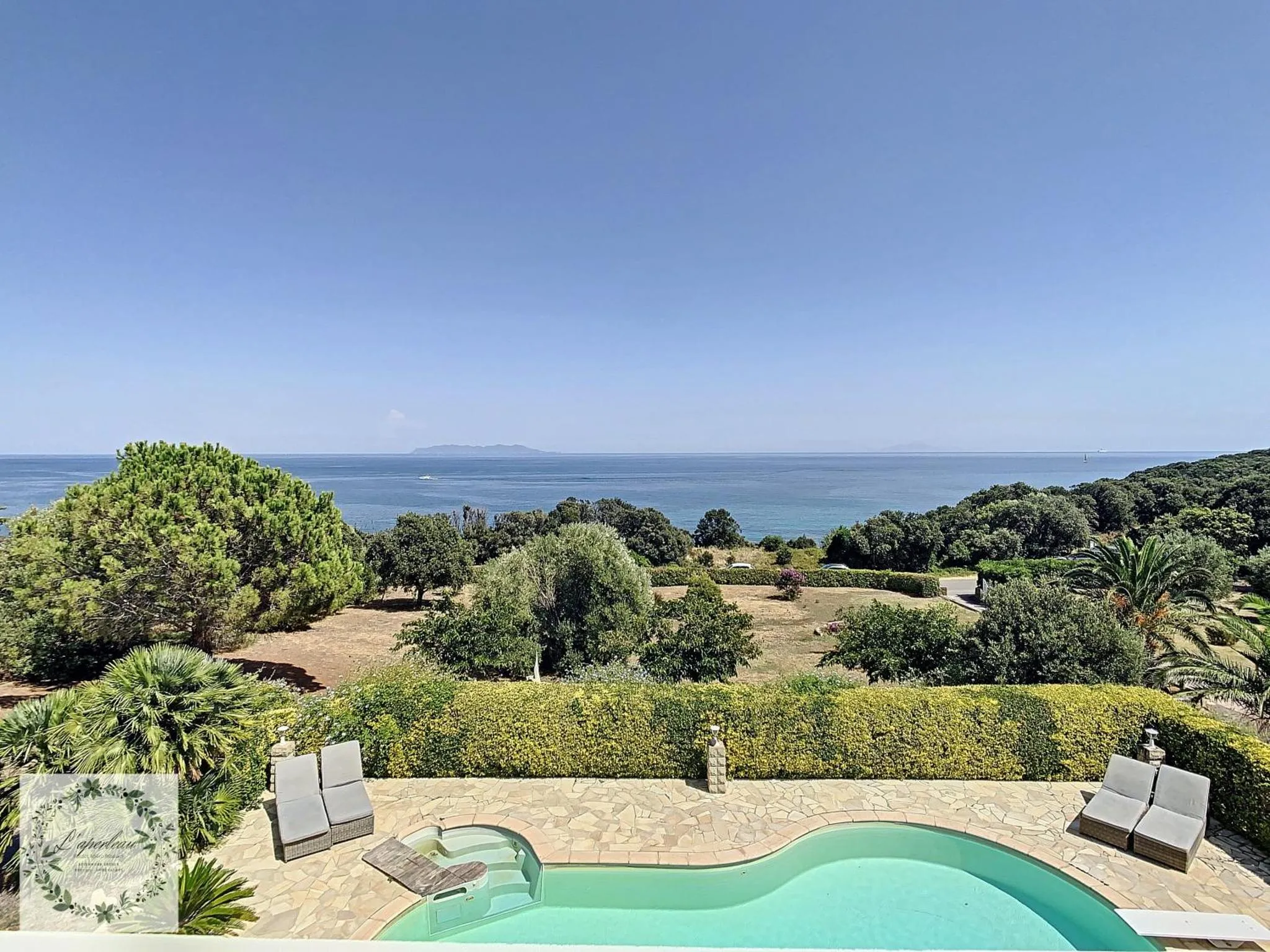 Terrasse avec piscine donnant sur la mer et la végétation.