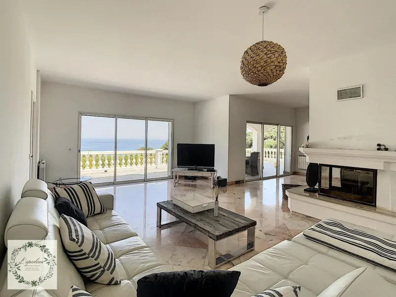 Espace de vie lumineux avec canapés et vue sur la mer.