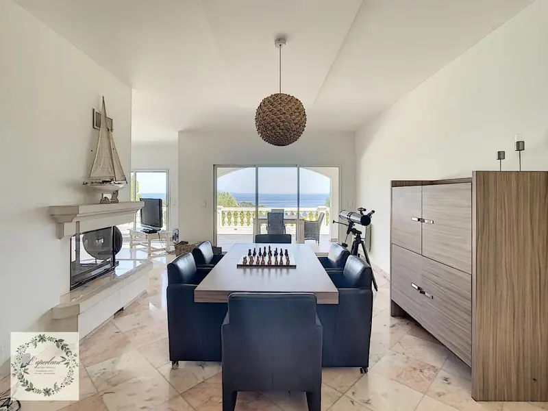 Une salle à manger lumineuse s'ouvre sur une terrasse avec vue sur la mer.