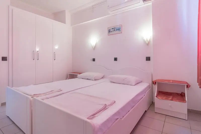 Une chambre lumineuse avec deux lits simples et une armoire.