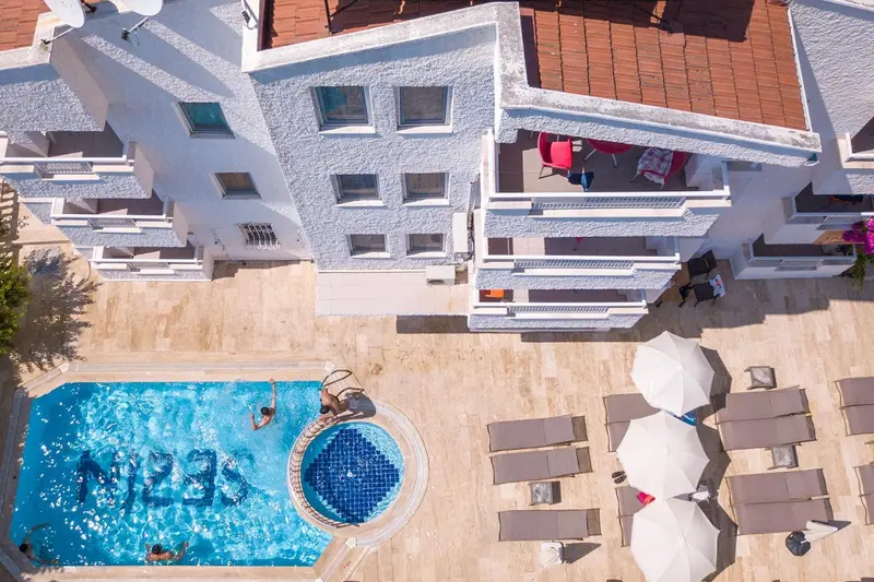 Vue aérienne d'un bâtiment blanc avec une piscine et des transats.