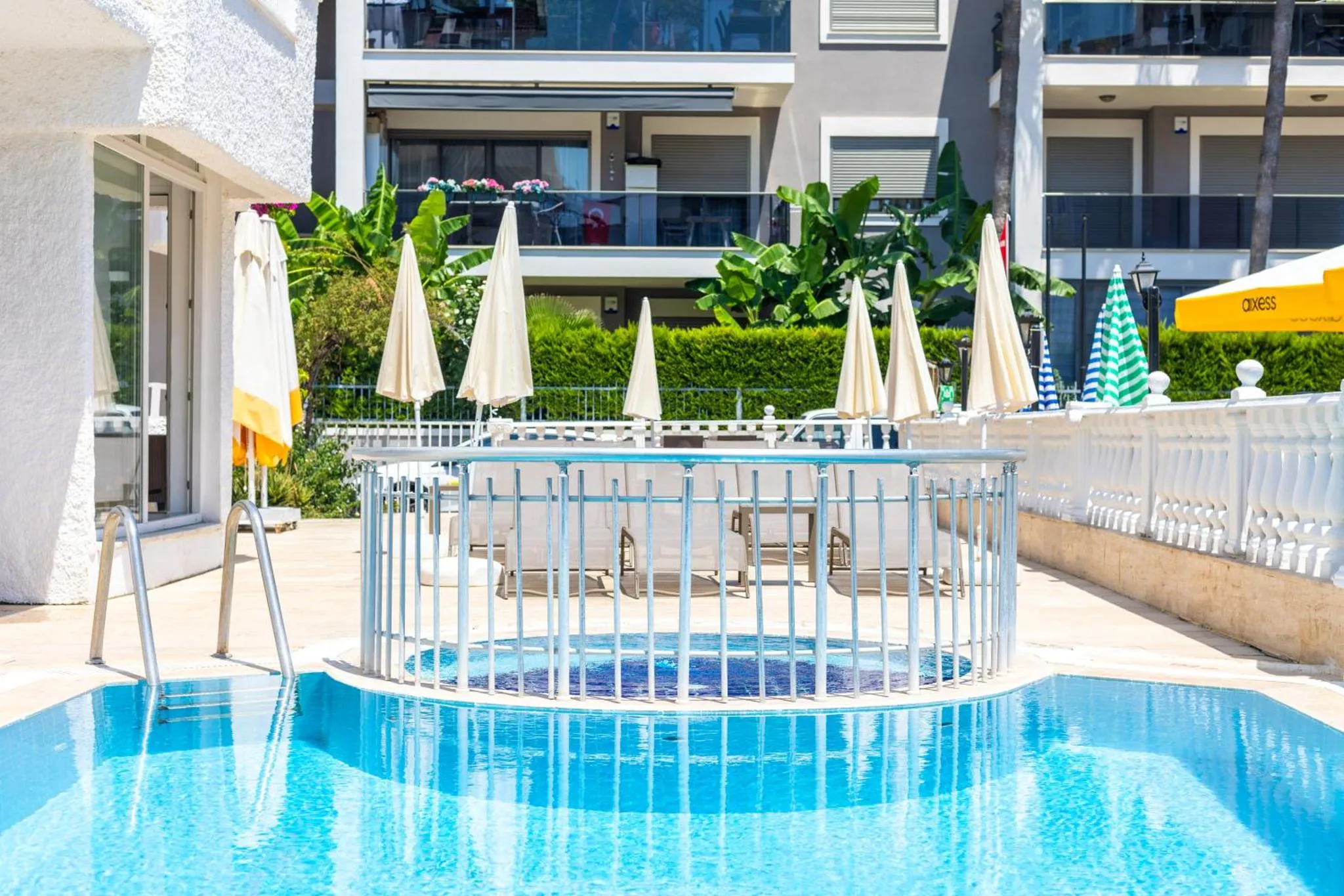 Petite piscine avec jacuzzi et transats sur une terrasse ensoleillée.
