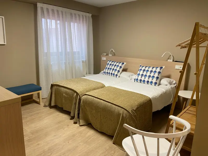 Une chambre lumineuse avec deux lits jumeaux et un fauteuil.
