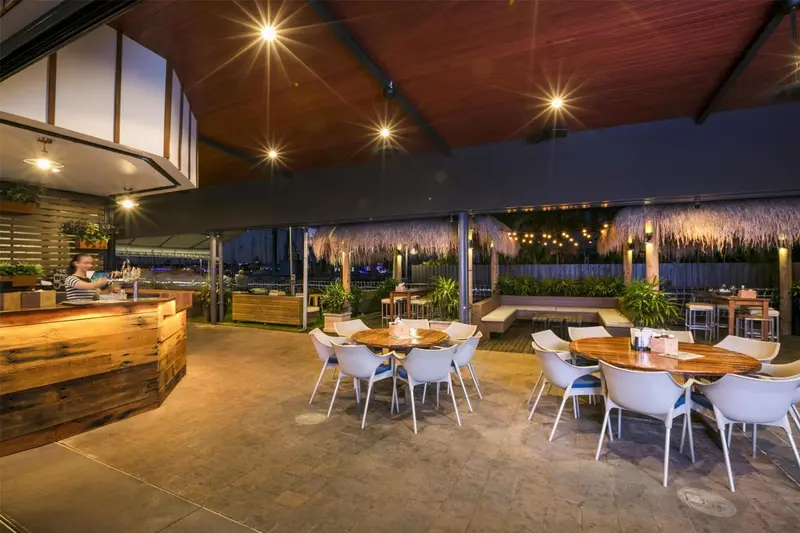 Espace extérieur avec bar et tables éclairées pour les repas.