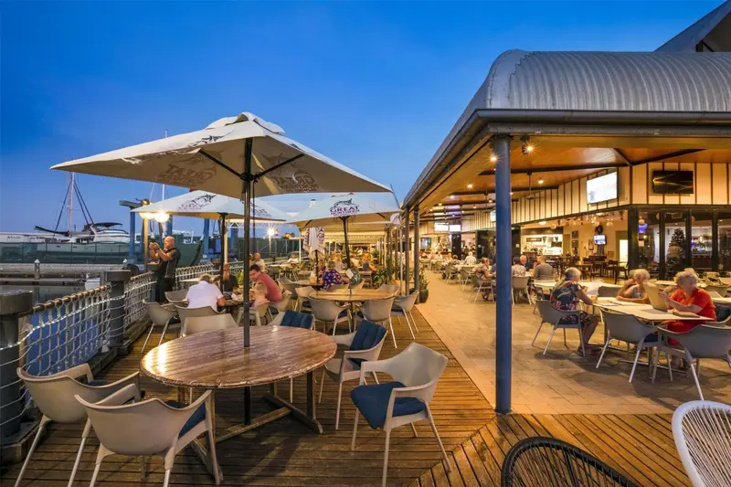 Terrasse de restaurant avec tables et parasols au bord de l'eau.
