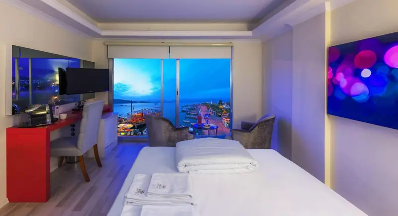 Chambre lumineuse avec un grand lit et une vue sur la mer.