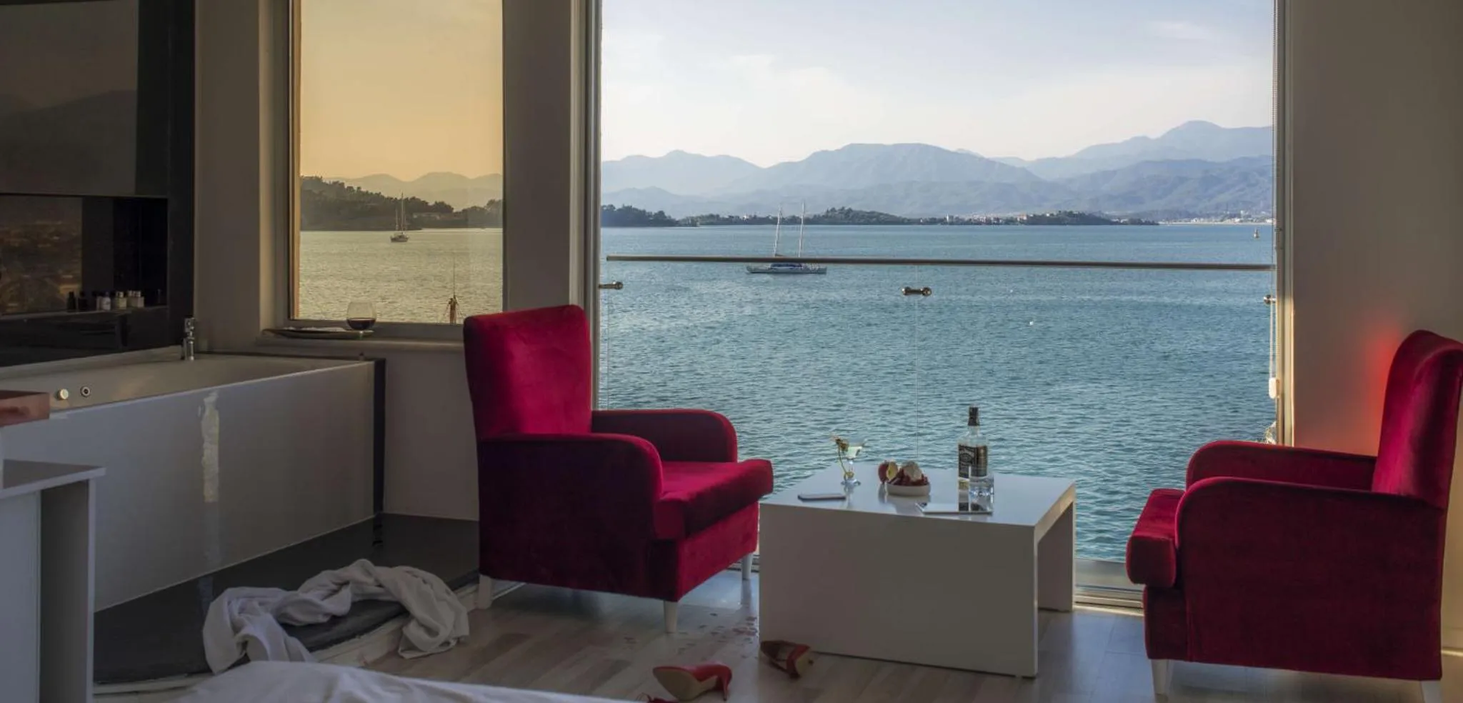 Espace de détente avec deux fauteuils rouges et vue sur la mer.