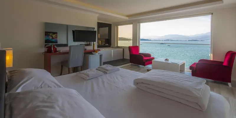 Chambre lumineuse avec un grand lit et une vue sur la mer.