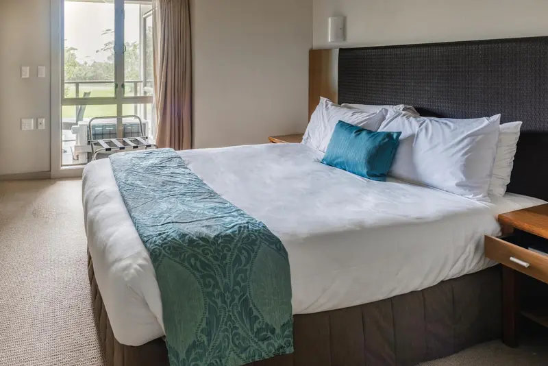 Une chambre lumineuse avec un grand lit recouvert d'une courtepointe turquoise.