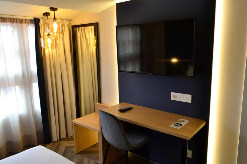 Une chambre lumineuse avec un bureau et une télévision murale.
