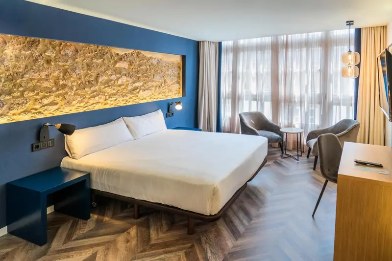 Une chambre lumineuse avec un grand lit et un coin salon.