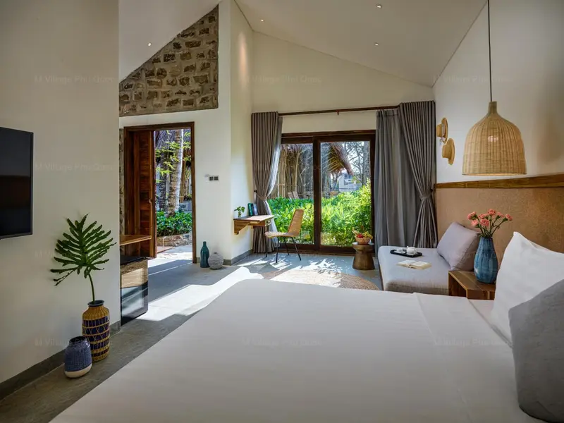 Une chambre lumineuse avec un lit et un bureau donnant sur une végétation luxuriante.