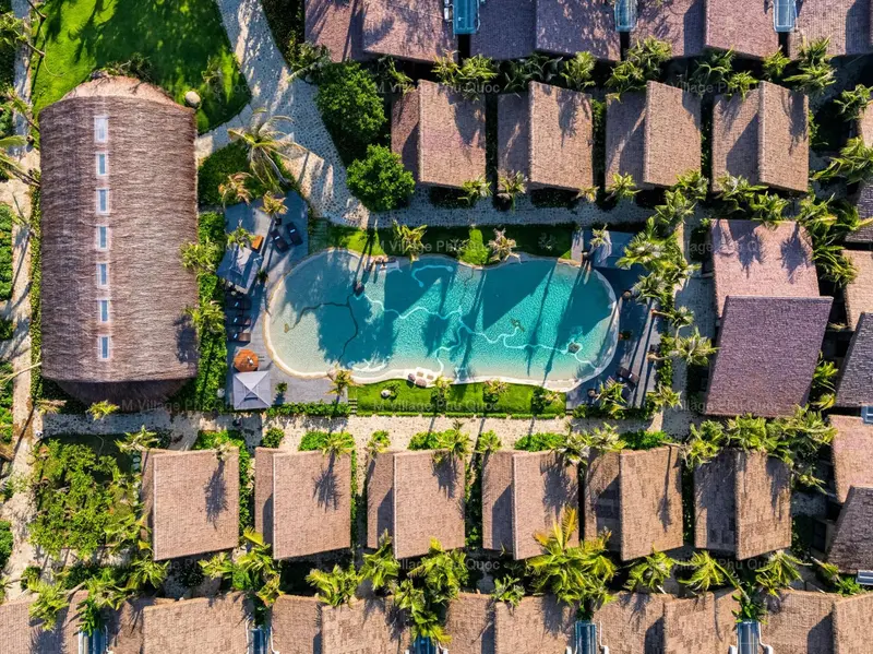Vue aérienne d'un complexe hôtelier avec des bungalows et une piscine turquoise.