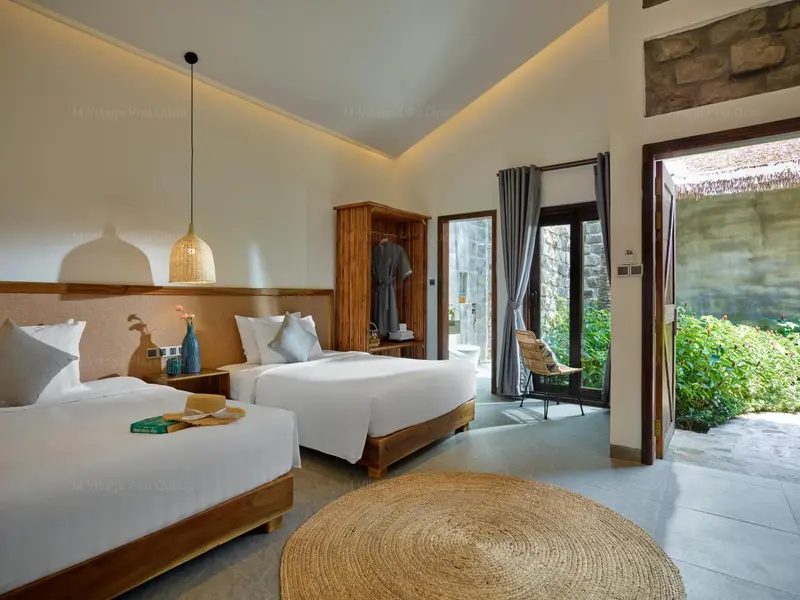 Chambre lumineuse avec deux lits simples et une décoration sobre.