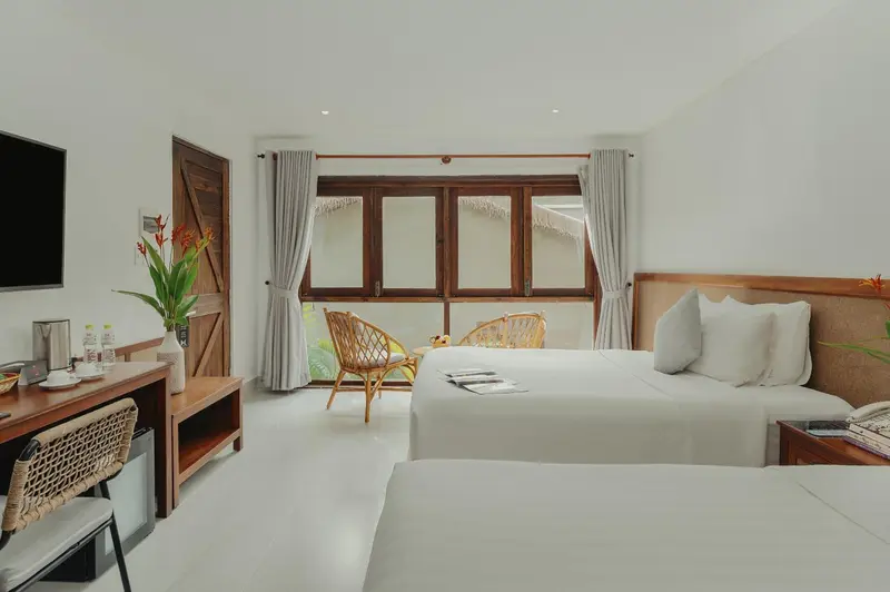 Une chambre lumineuse avec un grand lit et une vue sur un jardin.