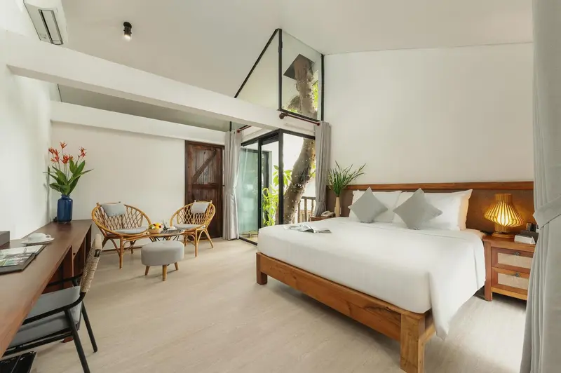 Une chambre lumineuse avec un lit double et un coin salon.