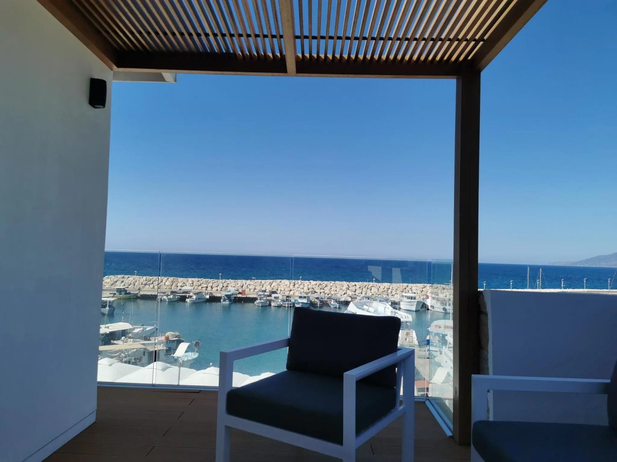 Vue sur un port de plaisance depuis une terrasse ombragée.