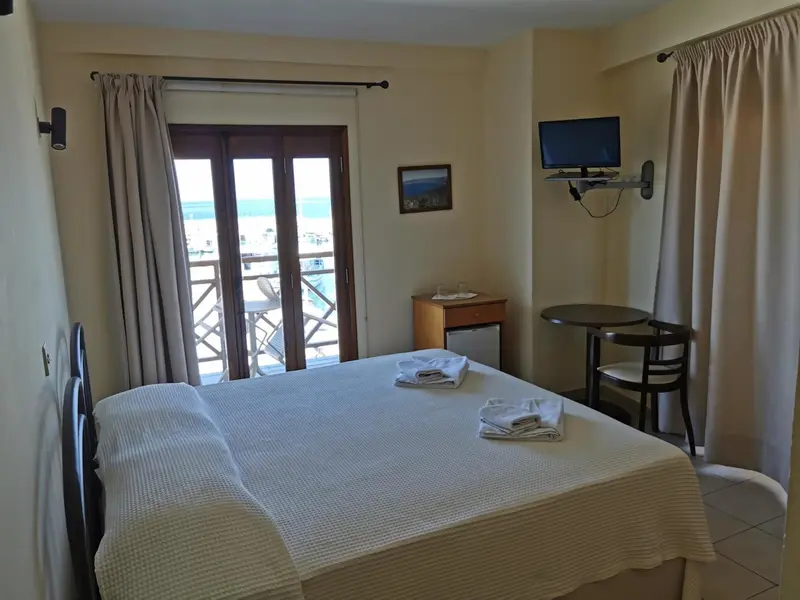 Une chambre lumineuse avec un lit et un coin repas donnant sur une vue mer.