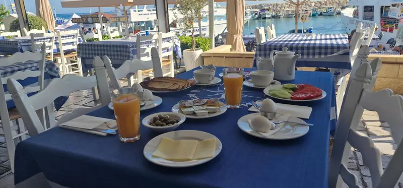 Une table est dressée pour le petit-déjeuner avec des jus d'orange, des œufs et des viennoiseries.