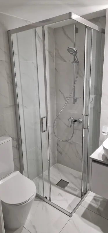 Une douche à l'italienne moderne avec parois vitrées et carrelage clair.