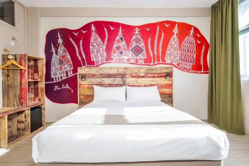 Une chambre lumineuse avec un grand lit et une décoration murale colorée.