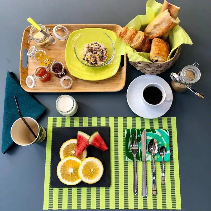 Un plateau de petit-déjeuner avec des viennoiseries, des fruits et des boissons est présenté sur une table.