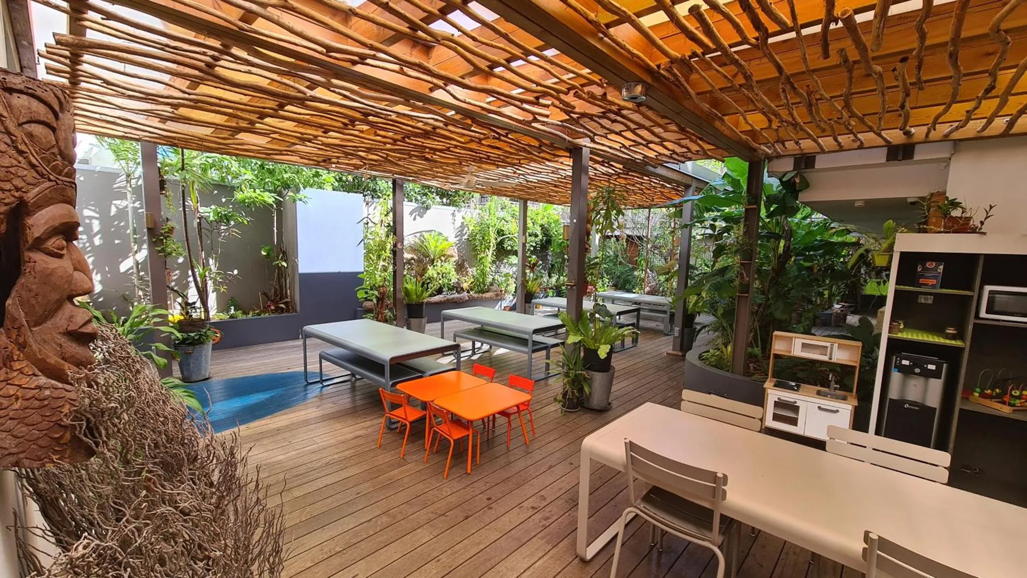 Espace extérieur aménagé avec tables et chaises sous une structure en bois.