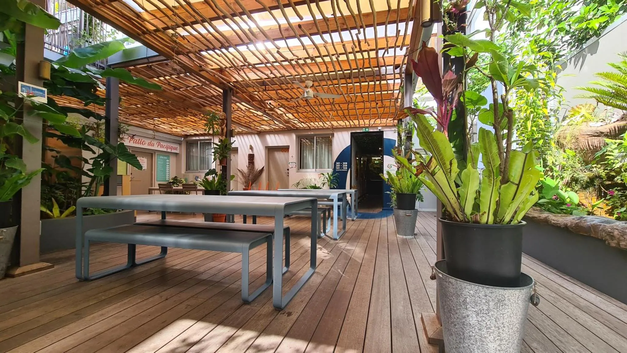 Terrasse ombragée avec tables et bancs en bois.