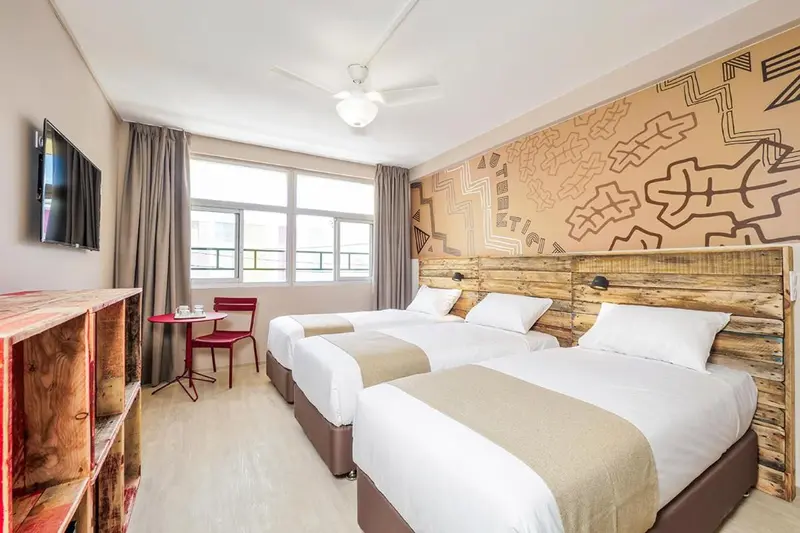 Chambre avec deux lits simples et une décoration murale colorée.
