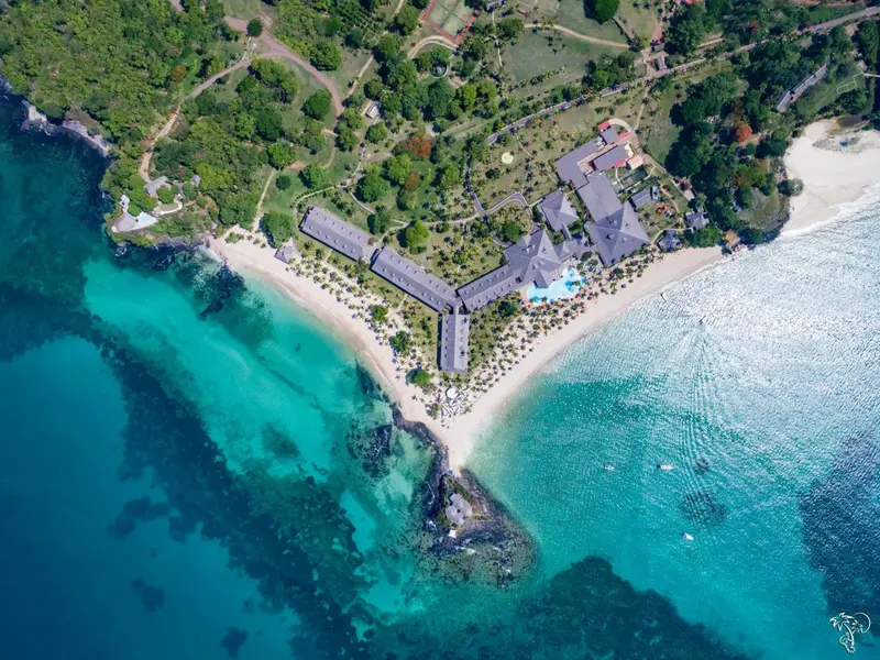 Vue aérienne d'un complexe hôtelier bordant une plage de sable blanc et une eau turquoise.