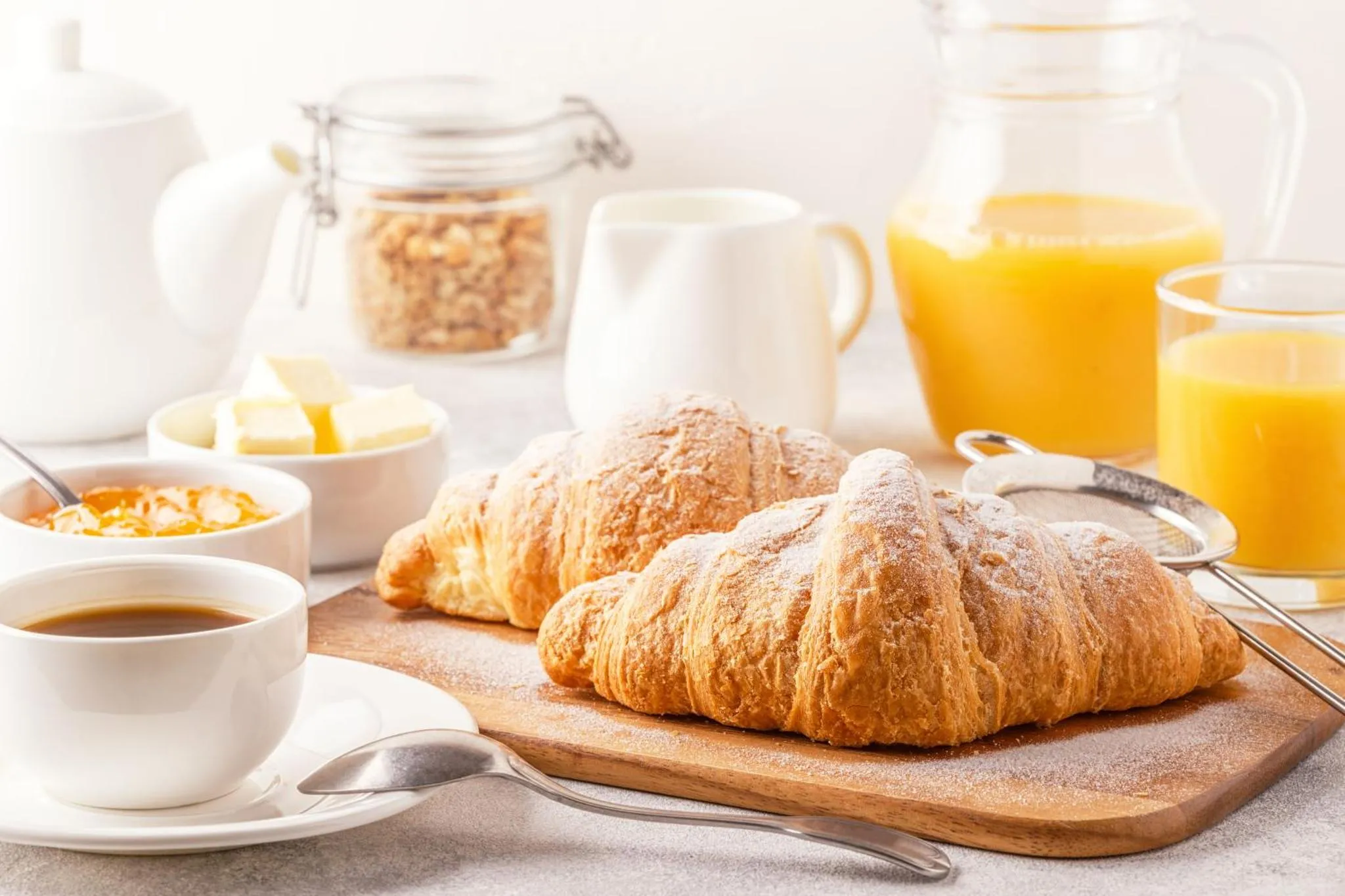 Une table présente des viennoiseries, du jus d'orange et du café.