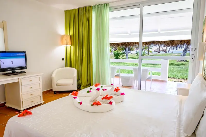 Une chambre lumineuse avec un lit décoré de fleurs et une vue sur la mer.