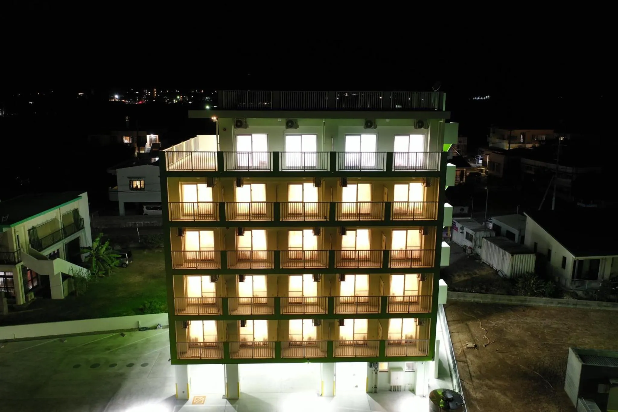 Bâtiment illuminé avec des balcons et des fenêtres allumées la nuit.