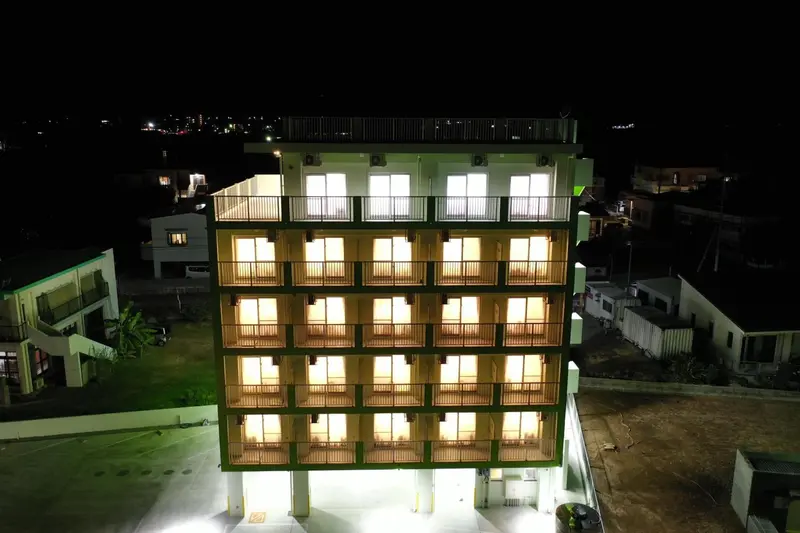 Bâtiment illuminé avec des balcons et des fenêtres allumées la nuit.