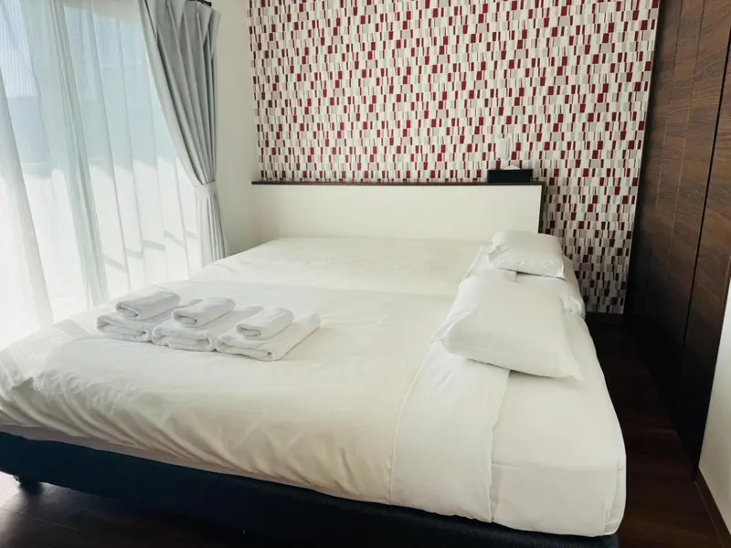 Une chambre avec un grand lit recouvert de draps blancs et de coussins.
