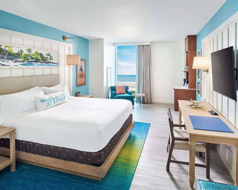 Chambre lumineuse avec un grand lit et vue sur la mer.