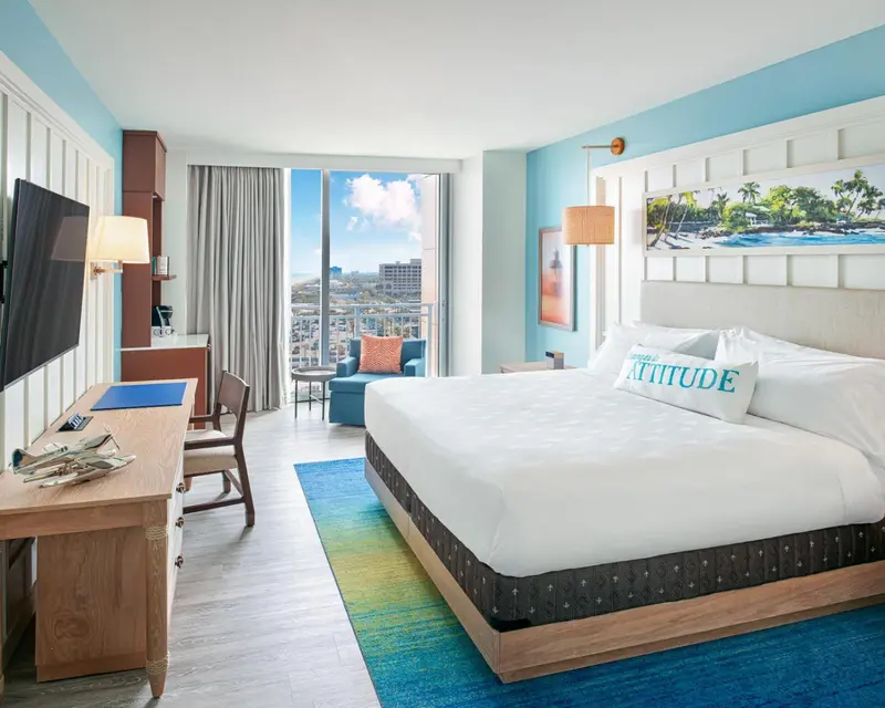 Chambre lumineuse avec un grand lit et une vue sur la mer.