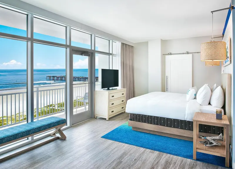 Chambre lumineuse avec un grand lit et une vue sur la mer.