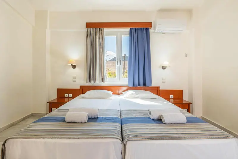 Une chambre lumineuse avec deux lits simples et une fenêtre.