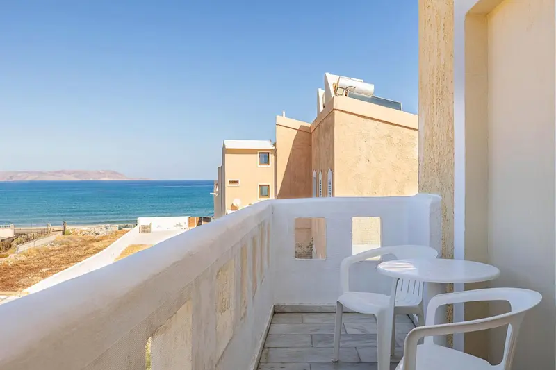 Vue sur la mer depuis un balcon avec mobilier blanc.