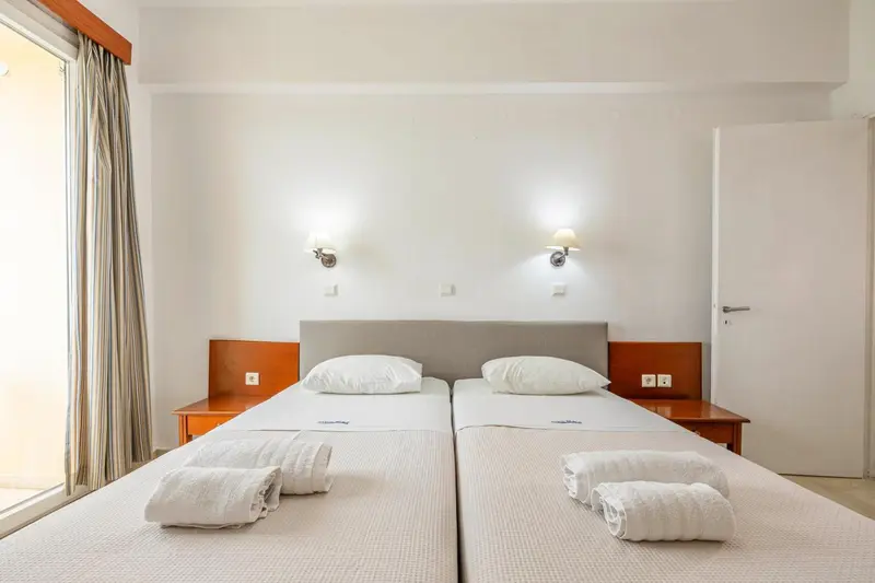 Une chambre lumineuse avec deux lits simples et des tables de chevet.