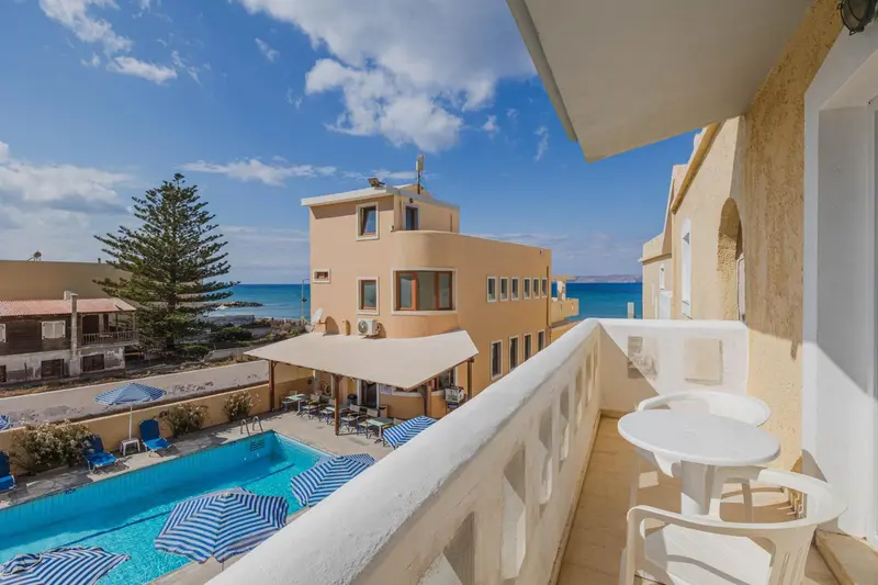 Terrasse avec vue sur une piscine et la mer.