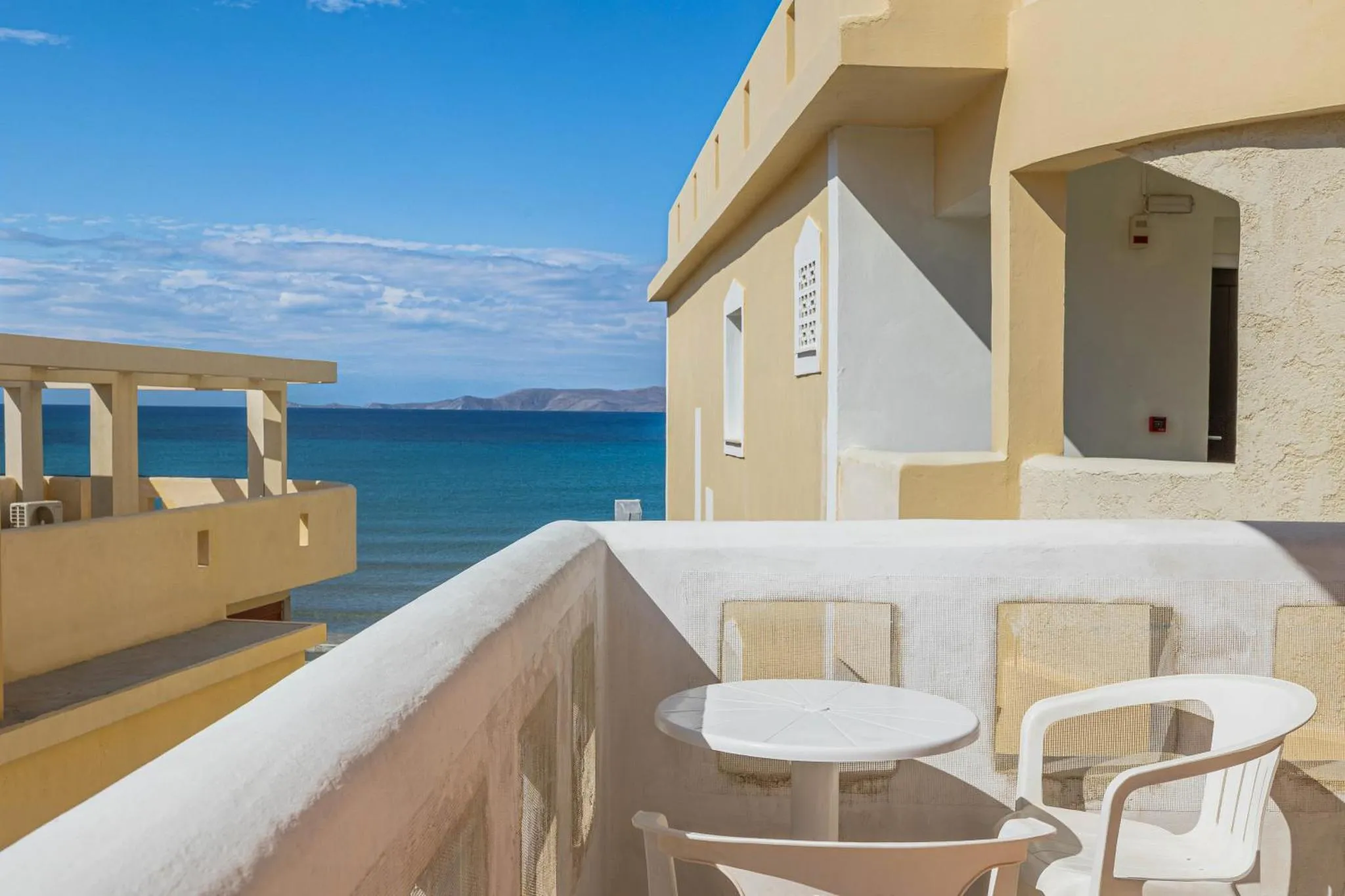 Terrasse avec table et chaises donnant sur la mer.