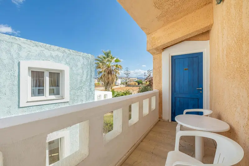 Une terrasse ensoleillée avec une table et des chaises blanches.